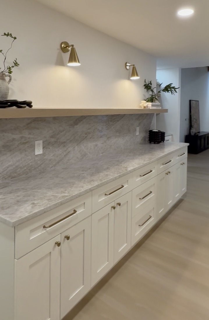 Kitchen remodel in Clearwater, FL with white shaker cabinetry, a full stone backsplash and brass wall sconces