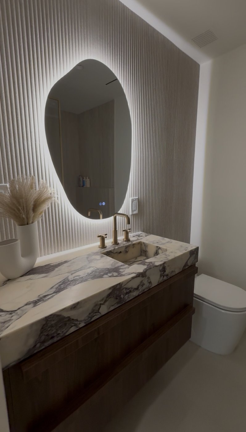 Vanity with backlit oval mirror and stone counter
