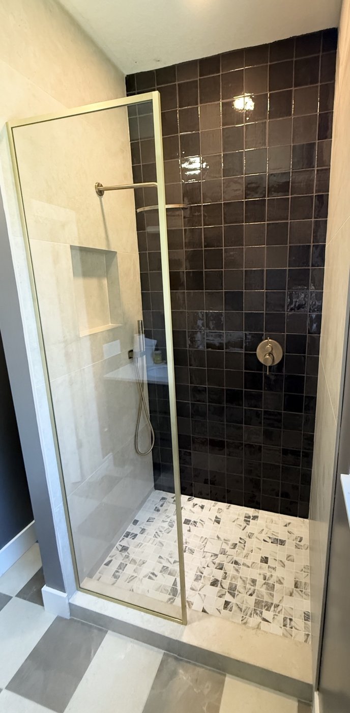 Dark tile walk-in shower with brass fixtures