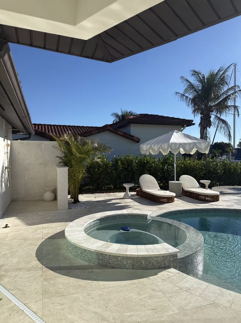 Exterior renovation in St. Petersburg, FL with a resurfaced pool, raised spa and travertine pool deck