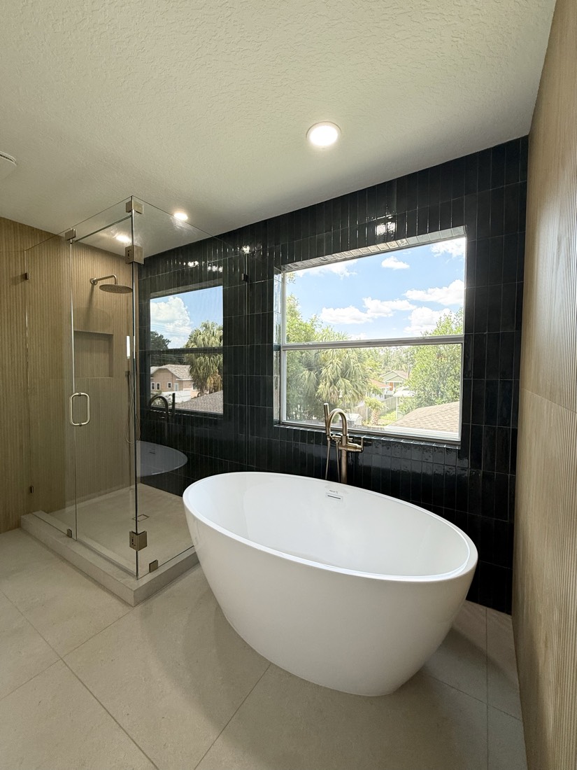 Bathroom remodel in Tampa, FL with a black tile feature wall, freestanding soaking tub and glass walk-in shower