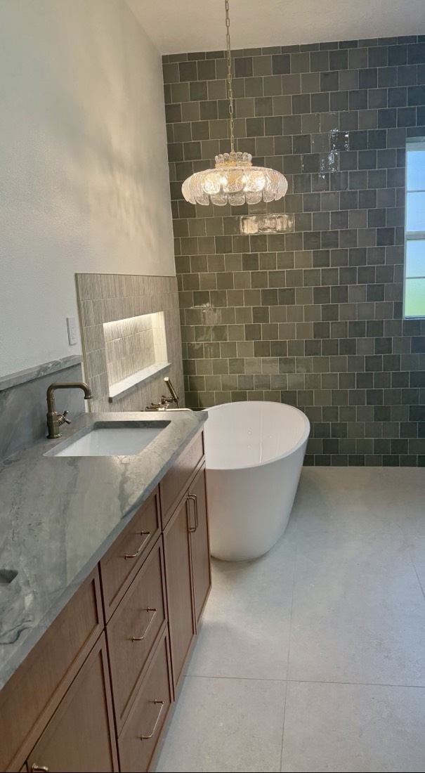 Bathroom remodel in Tampa, FL with green zellige tile, a freestanding soaking tub and a glass pendant light