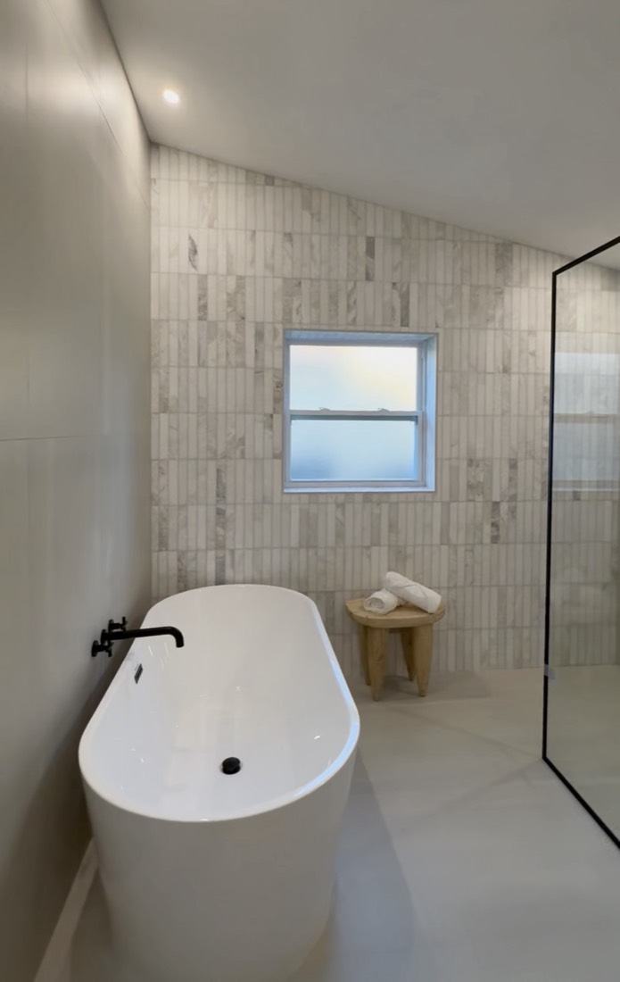 Bathroom remodel in Tampa, FL with a freestanding soaking tub set into a tiled alcove and a window above