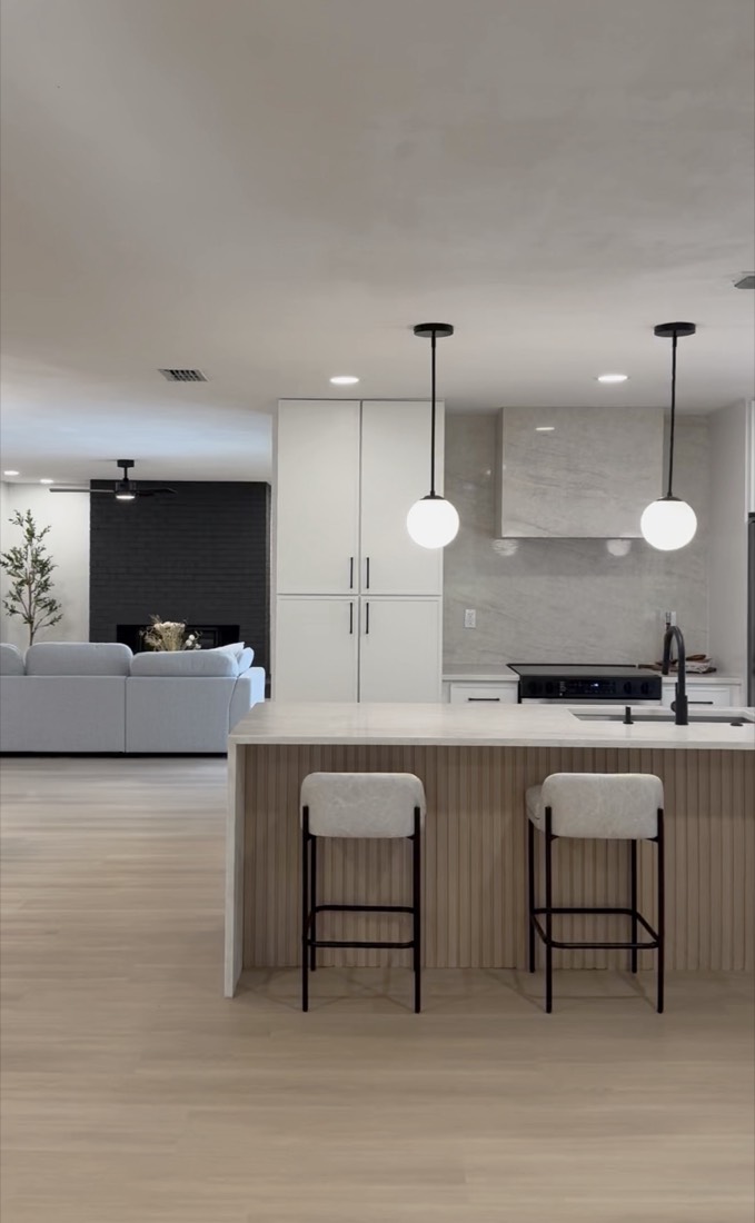 Kitchen remodel in Tampa, FL with a fluted oak island, globe pendant lighting and an open sightline to the living room