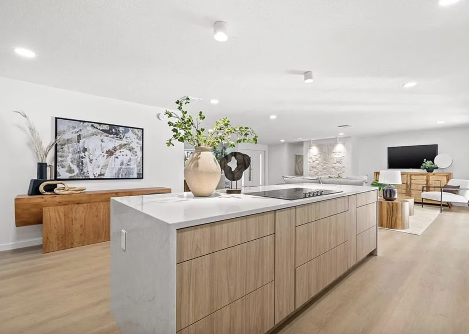 Open-plan kitchen renovation in Tampa, FL with a stone waterfall island, oak cabinetry and wide-plank floors