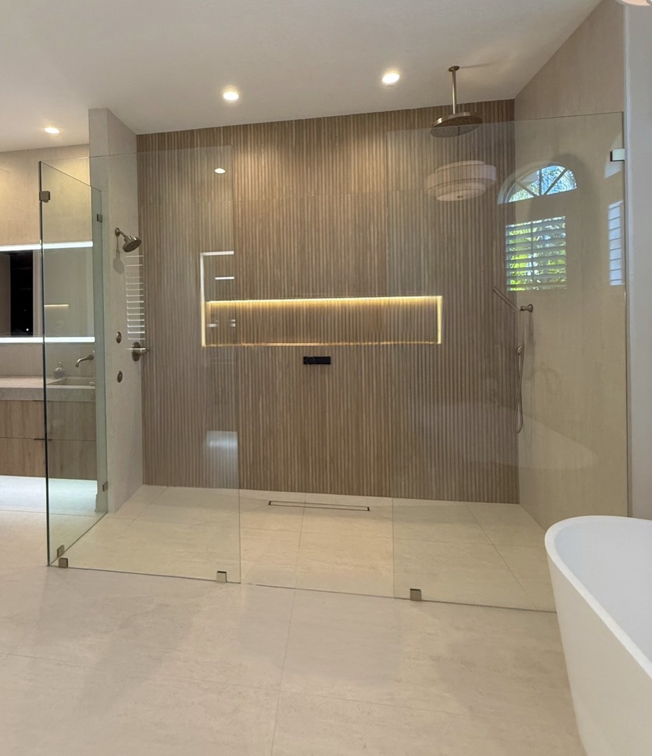 Luxury bathroom remodel in Tampa, FL with an oversized curbless walk-in shower, wood-look tile and a lit niche