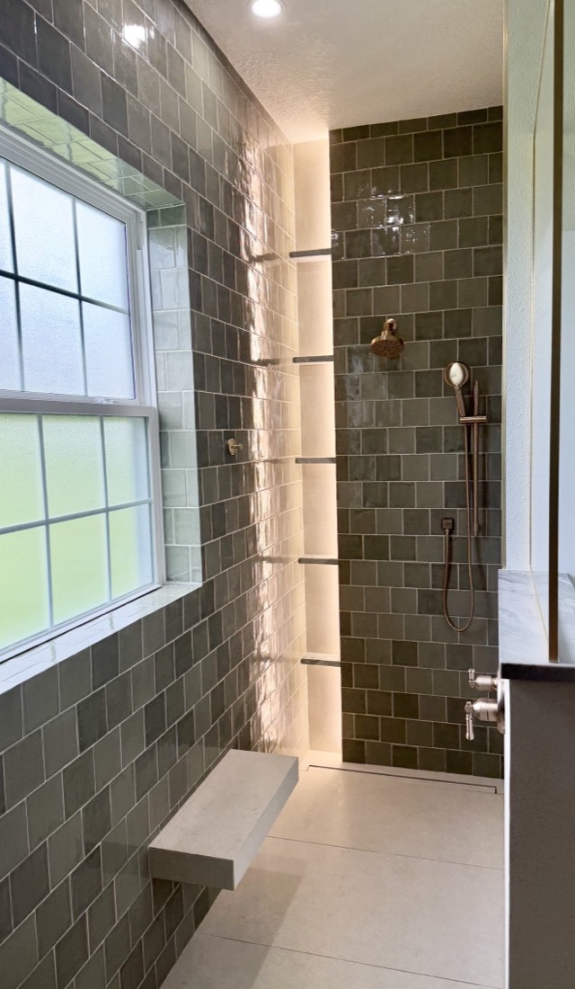 Walk-in shower remodel in Tampa, FL with green square tile, a floating bench and a lit vertical niche